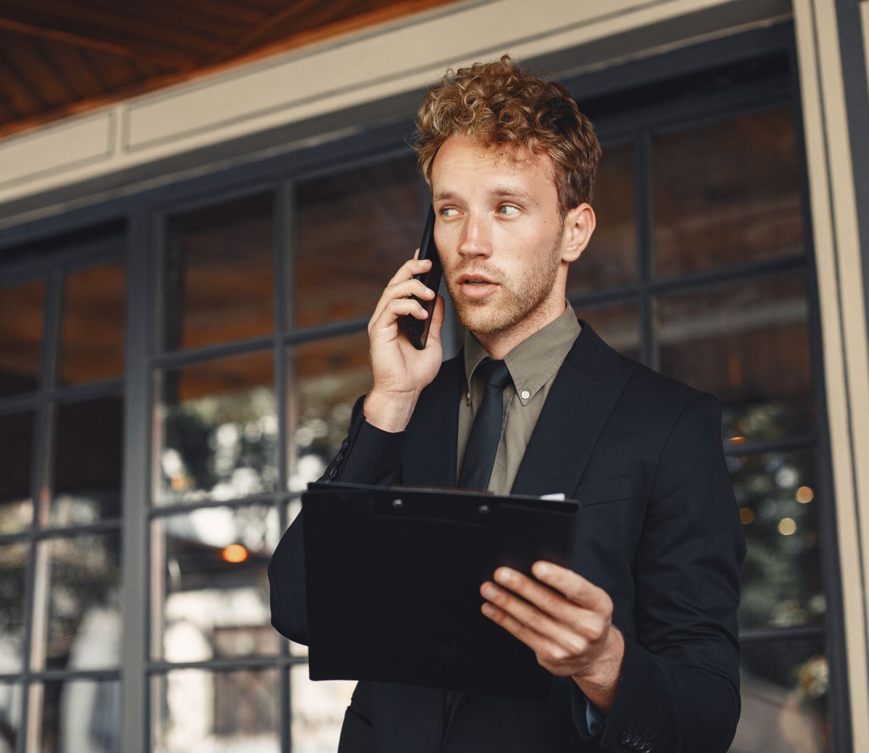 A business professional taking a call with a clipboard in hand