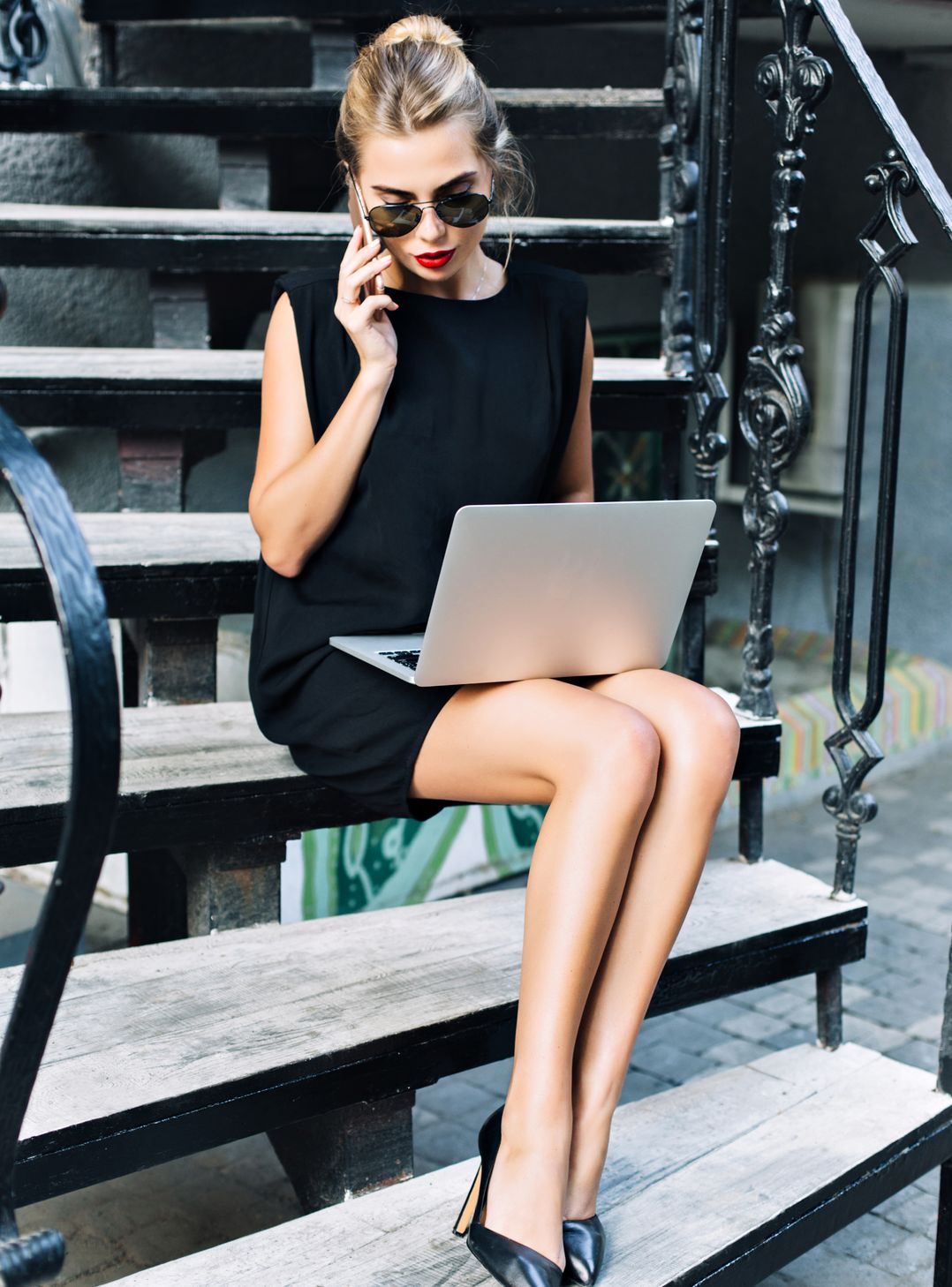 A woman sits on some steps with a laptop