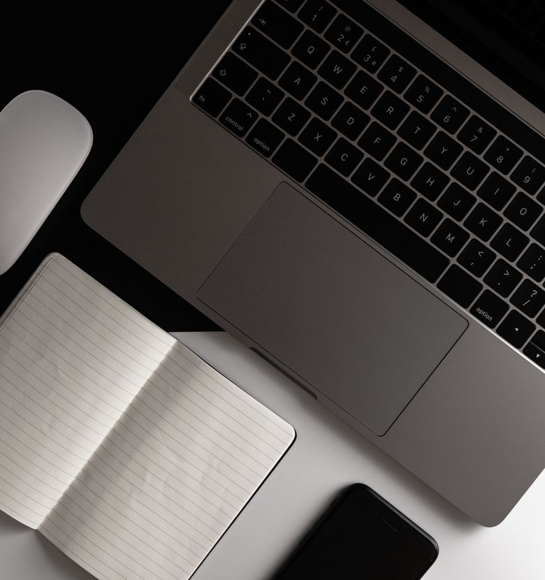 A laptop on a desk with a notepad and phone